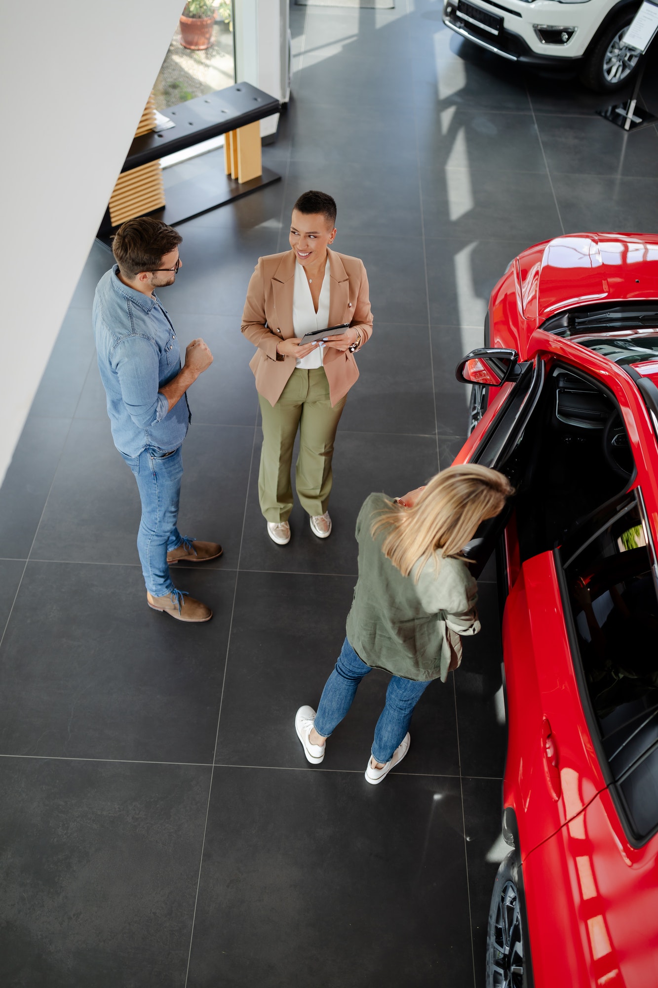 couple choosing and buying car at car showroom. Car saleswoman helps them to make right decision.